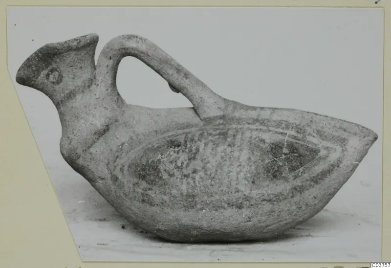 Bird-shaped pottery vessel with a strap handle arching over its back and a spout-like head at the left