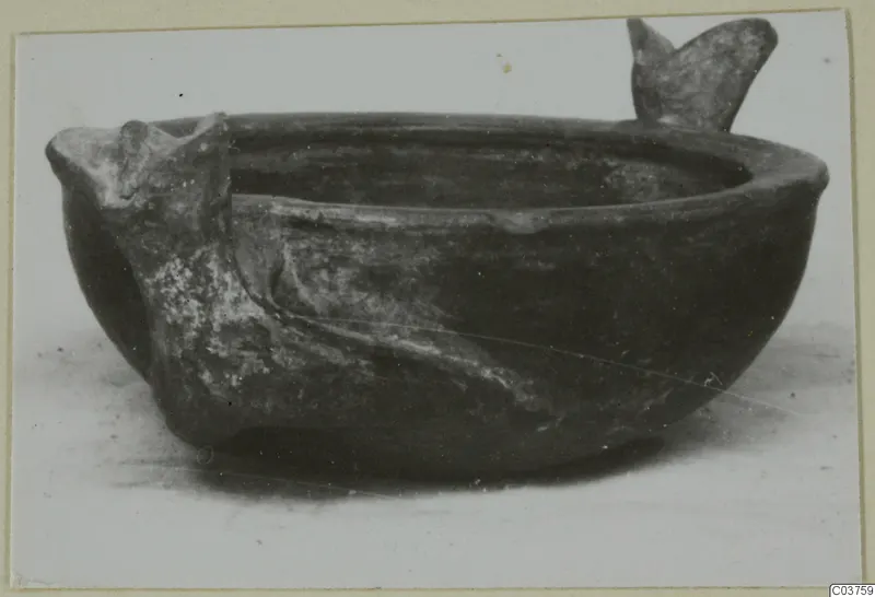 Grey polished ware bowl with two projecting lugs, photographed on a pale surface