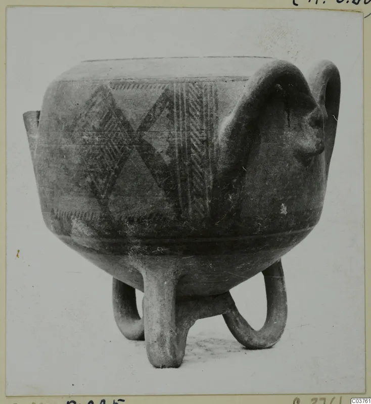 Pottery vessel on three looped legs with dark painted geometric bands and a large loop handle on the right