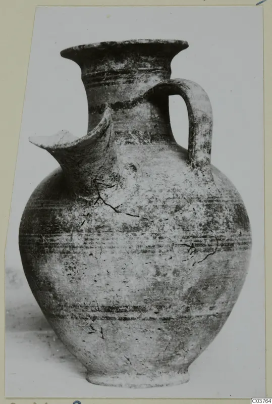 Pottery jug with a pinched spout, strap handle and horizontal bands, photographed on a card mount