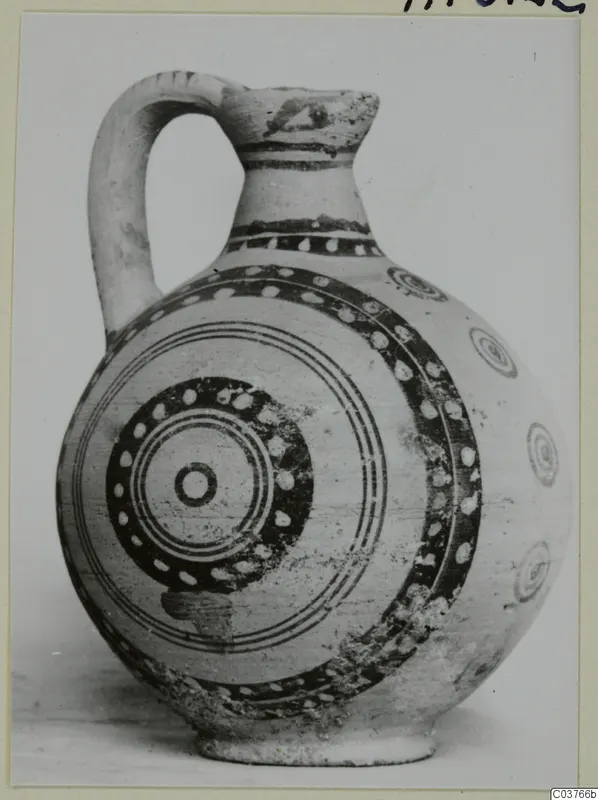 Painted pottery jug with a strap handle and concentric circle decoration, shown on a card mount