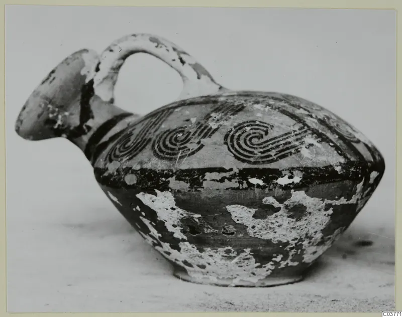 Pottery White Painted VI vessel with a beaked spout, strap handle and black spiral decoration