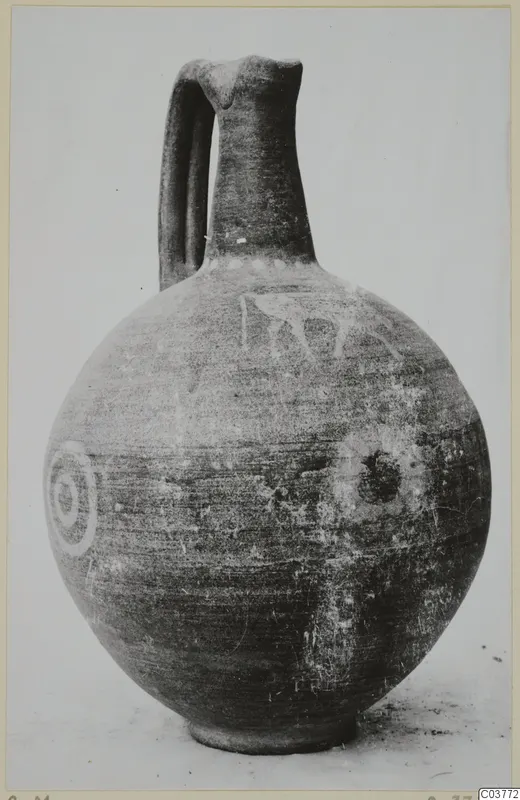 Round jug with a tall neck, strap handle, and pale painted concentric circles and a figure on its body