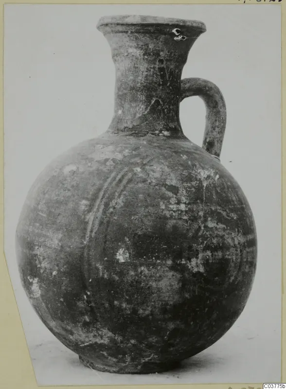 Globular jug with a tall flaring neck and a single loop handle, photographed on a card mount