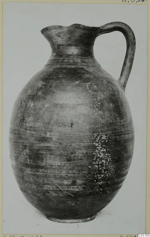 Tall jug with a wide globular body, a trefoil-style mouth and a strap handle, photographed against a plain background