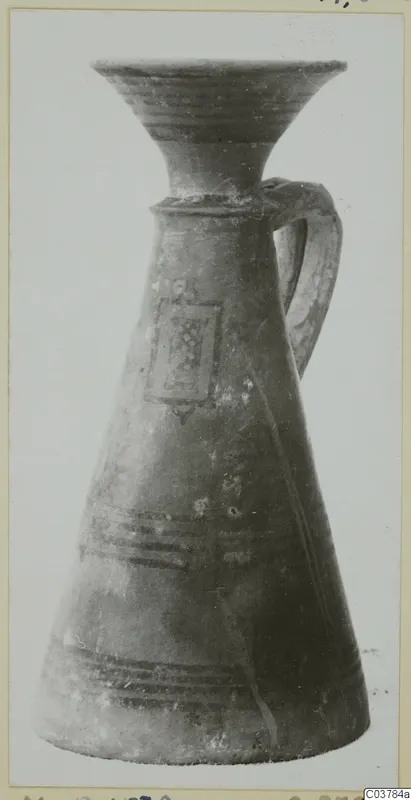 Painted pottery jug with a flaring mouth, strap handle and a rectangular panel with a pattern on the body