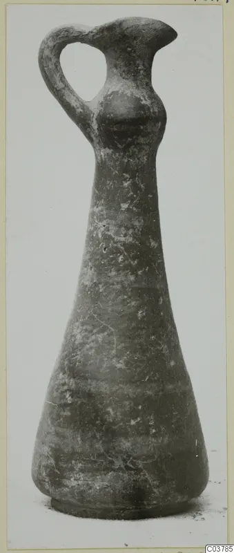 Pottery jug with a loop handle, tall neck and flaring rim, shown upright against a plain background