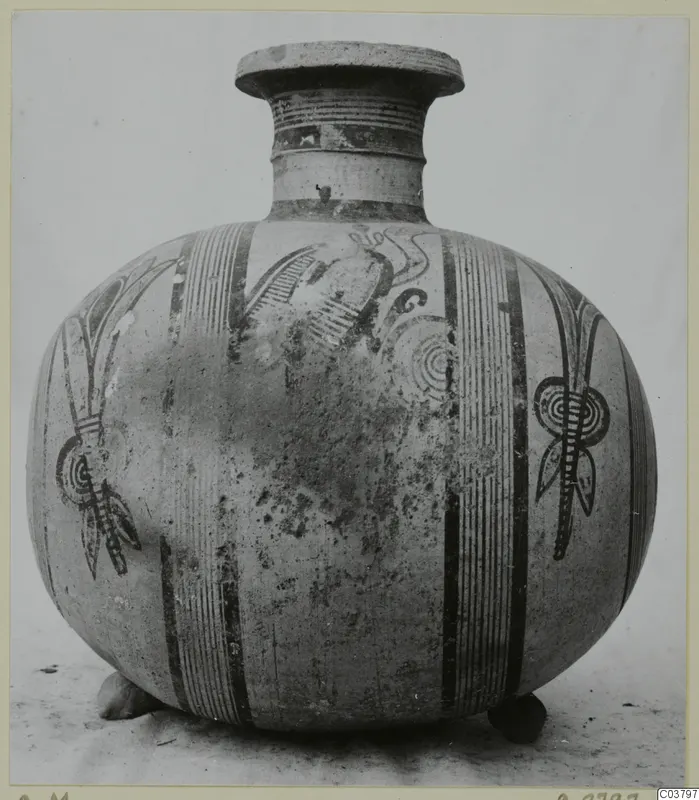 Jug with a flat-rimmed mouth, painted vertical bands and stylised plant motifs, shown from the front against a plain backdrop