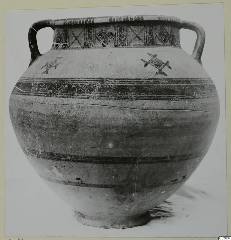 Two-handled pottery jar with painted bands and a cross-hatched rim band, photographed against a plain background.