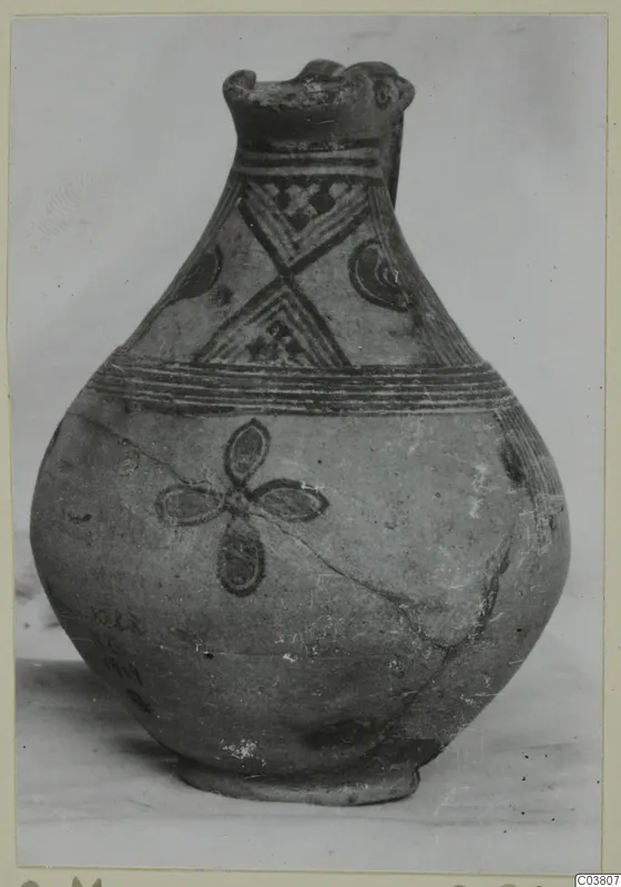 Painted pottery jug with a lipped mouth, dark banded decoration and a four-petalled motif on the body