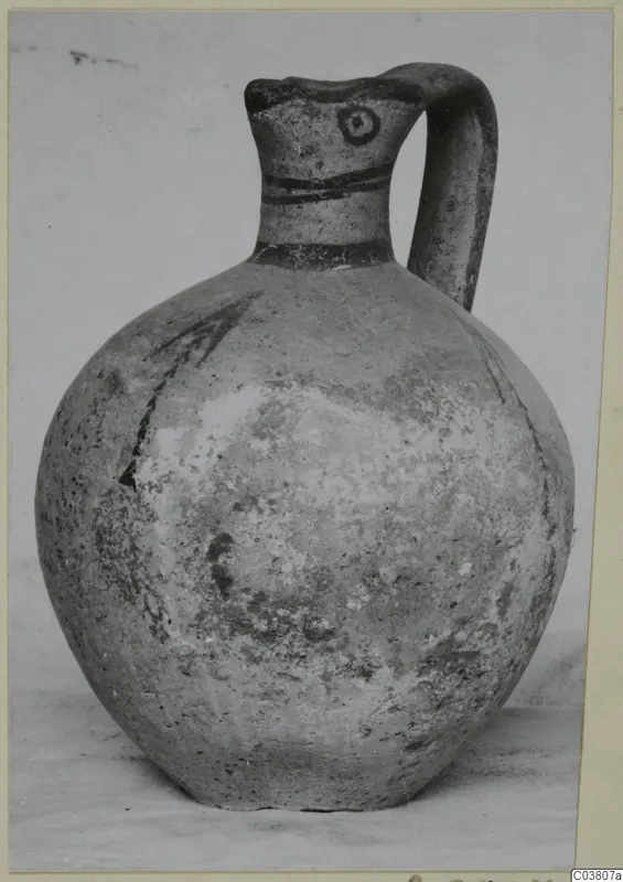 Round-bodied jug with a single loop handle and dark painted bands on the neck, shown on a plain surface.