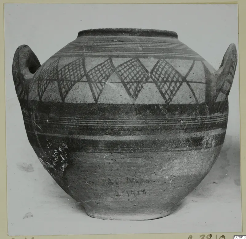 Painted two-handled jug with lattice-filled triangles and horizontal bands, photographed against a pale background
