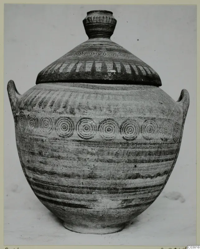 Lidded jar with concentric circle bands and hatched decoration, photographed upright against a plain background.