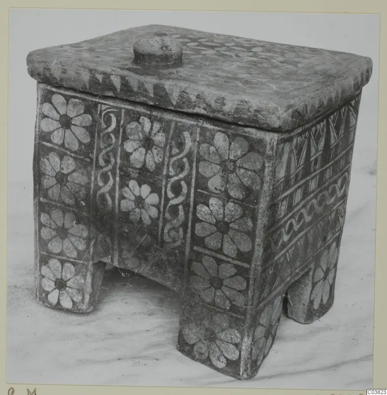 Painted pottery box with lid, round knob and four short feet, decorated with white flower motifs and bands