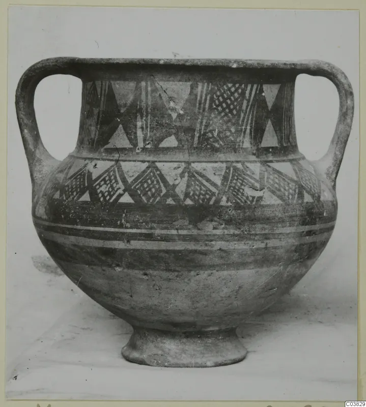 Two-handled pottery jar with a footed base and painted geometric bands, photographed against a plain background.