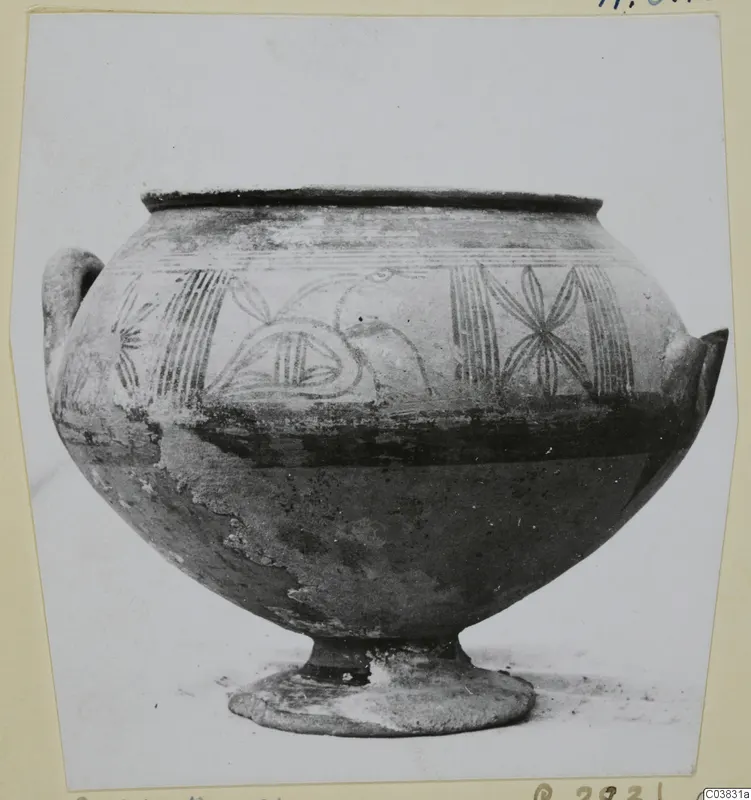 Painted pottery vessel with a wide body, two small handles and a short footed base, shown in a photograph mounted on a card.