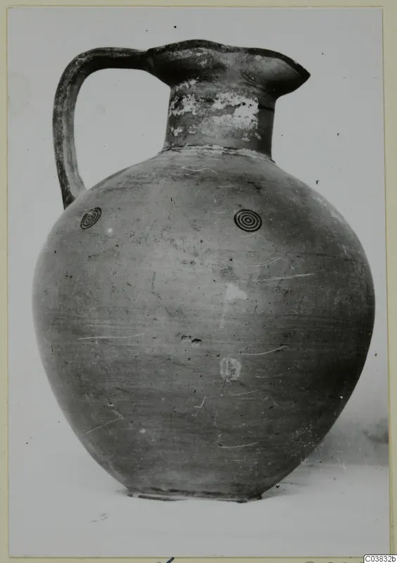 Pottery jug with a single strap handle, a tall neck and concentric circle motifs on the rounded body