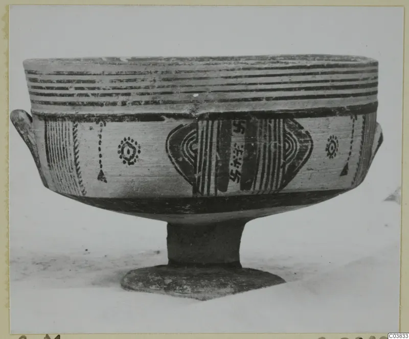Painted pottery stemmed bowl with two small handles, black bands and motifs on a cream surface