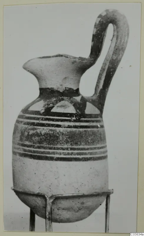 Pottery Bichrome I vessel with one loop handle and dark painted bands, shown on a wire stand