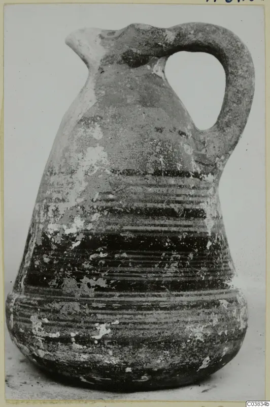 Pottery jug with a single loop handle and banded painted decoration, shown on a plain background