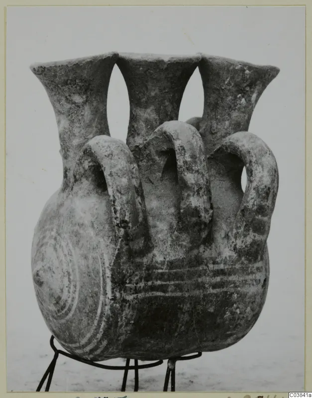 Three-necked vessel with looped handles on a wire stand, with concentric circle decoration on the side