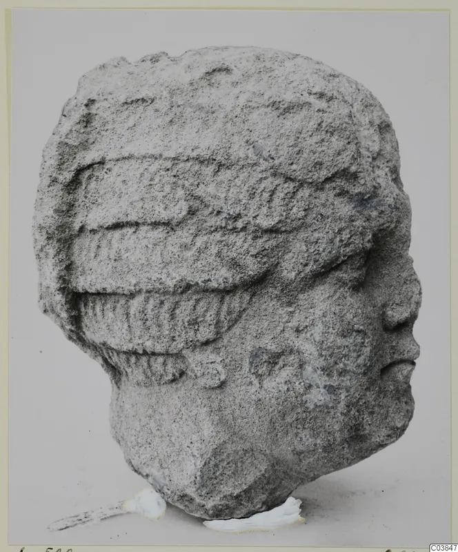 Stone head from Soli, shown in profile facing right, with a ridged headdress.