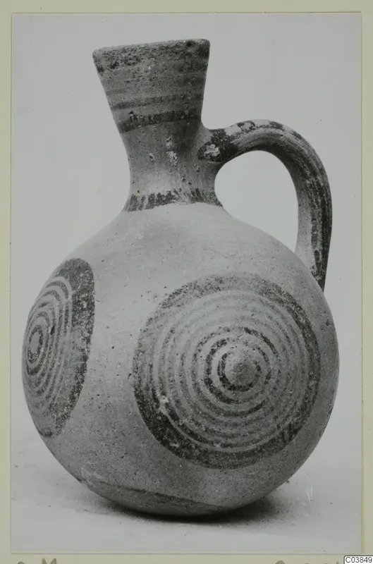 Pottery jug with a flaring neck, one handle and dark concentric circle decoration on the body