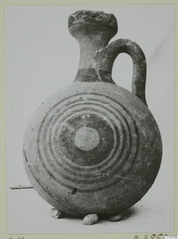 Round jug with concentric painted rings on its body, a tall flaring neck and a loop handle