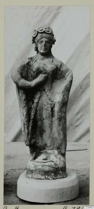 Terracotta figurine of a standing woman with a rolled headdress and draped garment, on a round white base