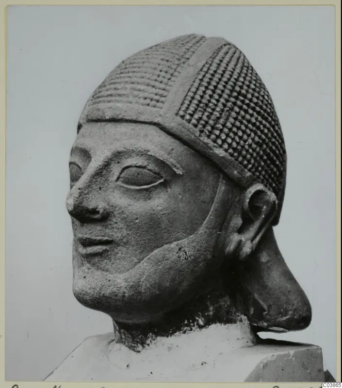 Limestone head sculpture from Amathus wearing a patterned cap, shown in three-quarter view on a block base.