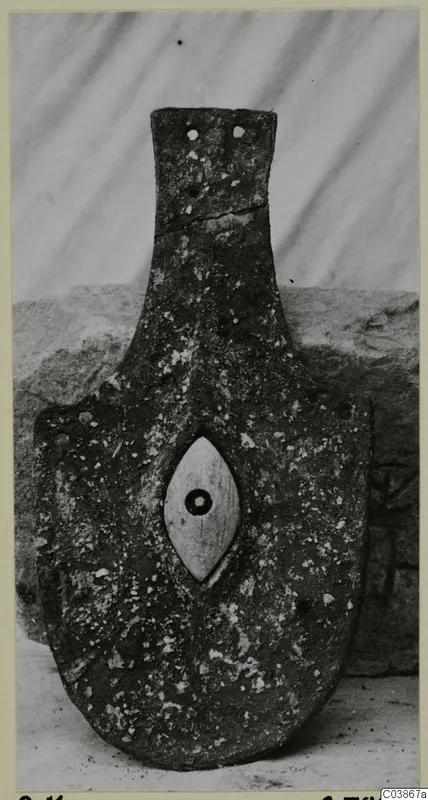 Bronze horse-trappings, a corroded metal plate with a central oval boss and a tang-like upper section.