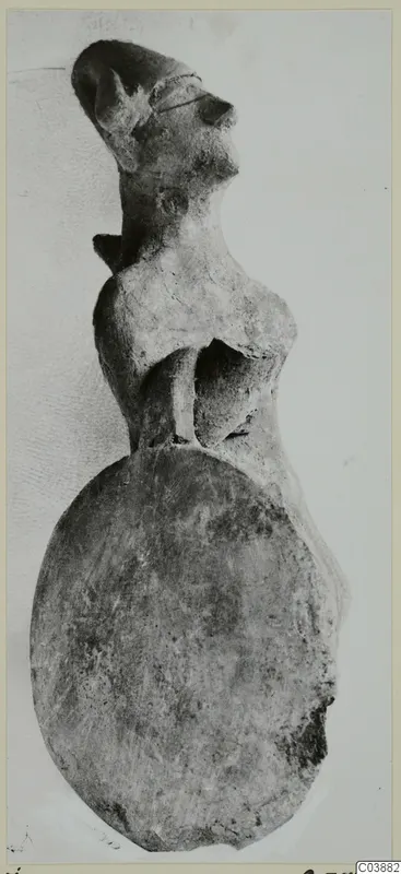 Terracotta figurine of a human figure with a large flat round base, photographed against a pale background