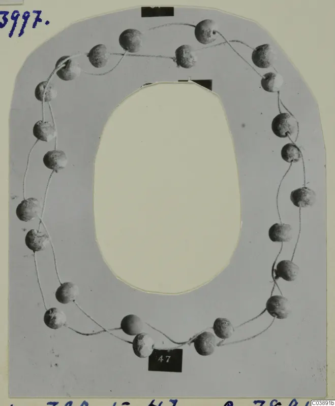 Necklace of rounded beads strung on fine thread, laid out on a grey card mount