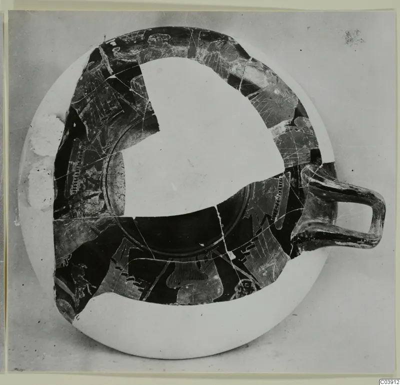 Shallow pottery vessel with a single handle, seen from above, partly reconstructed with pale infill