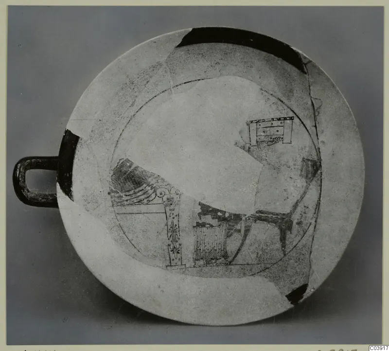 Shallow pottery dish with a loop handle and dark painted motifs, reconstructed from fragments