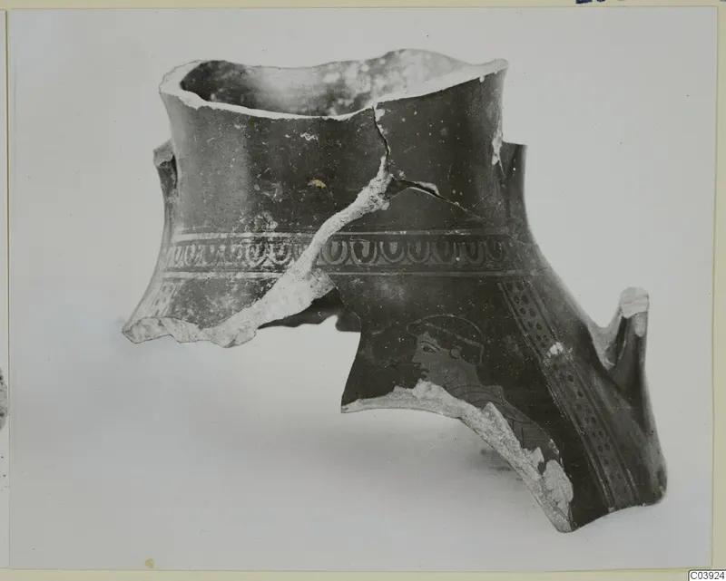 Broken pottery vessel fragment with a band of looped pattern and a human head in profile