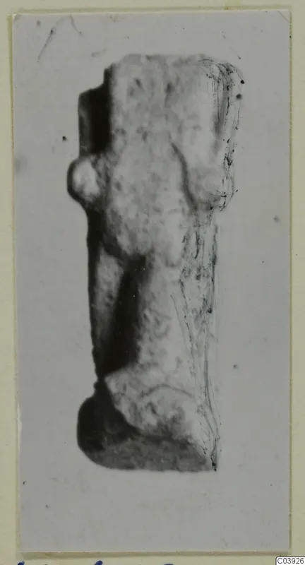 Worn, pale fragment of a figure from Vouni, shown upright on a mounted photograph