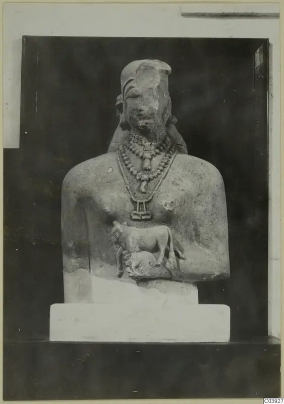 Limestone sculpture of an upper body with layered necklaces and a small animal carved at the chest.