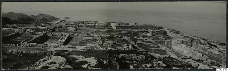 Excavated ruins of the palace at Vouni, with stone walls, hills to the left and the sea beyond