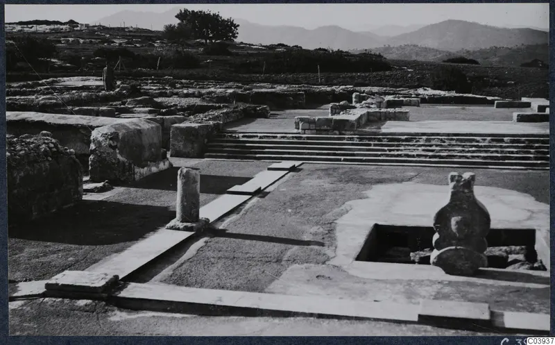 Stone steps, a column and a large vessel-like object among ruins at the palace at Vouni, with hills beyond
