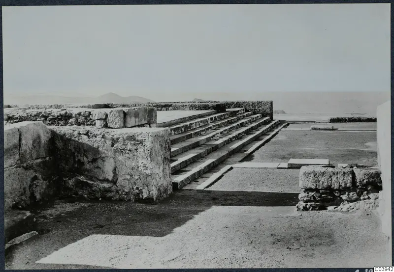 Stone steps and low walls among ruins at the palace at Vouni, with hills and sea on the horizon.