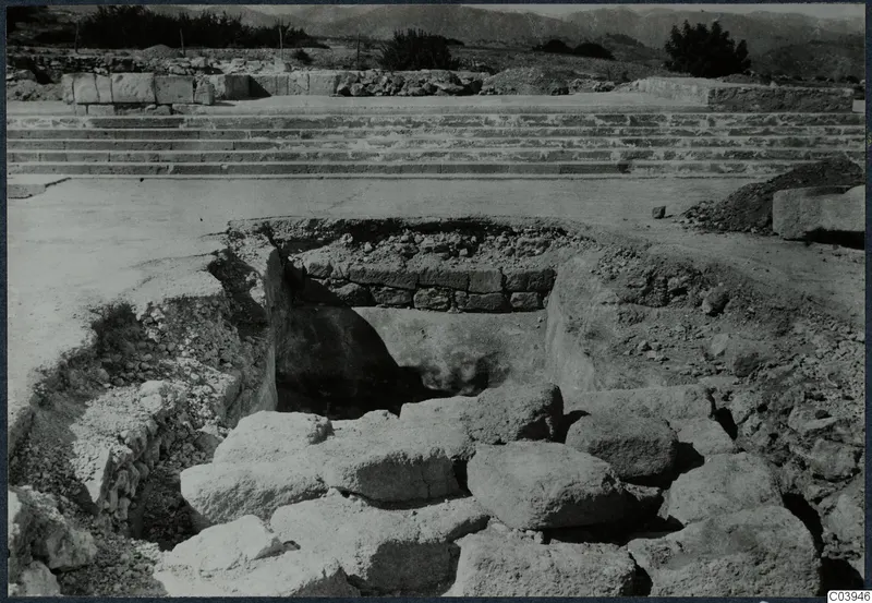 Excavation at Vouni showing large fallen stones in a trench, with a broad stone staircase behind.