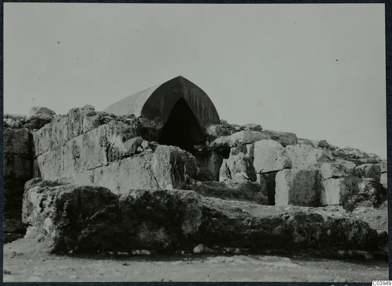 Large stone blocks and a canvas tent over an arched opening at the palace at Vouni