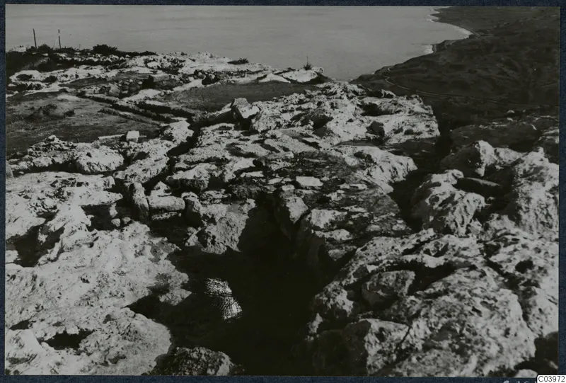 Stone ruins at Vouni with a water-filled channel between blocks and the sea beyond