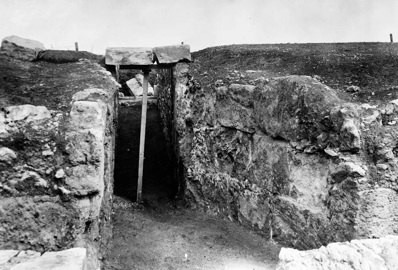 Narrow stone-walled passage at Soli, its top spanned by two large stone slabs propped on a timber beam and upright post.