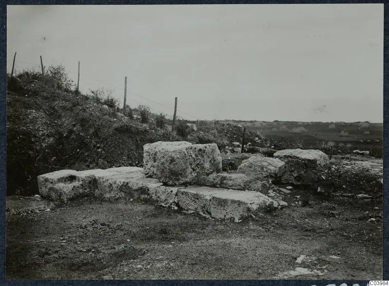 Large cut stone blocks forming a step-like structure on a slope at the theatre at Soli, with a wire fence behind.