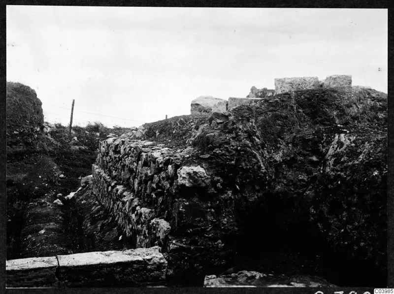 Excavated stone wall and cut blocks at Soli: the theatre, with a wire fence and posts behind