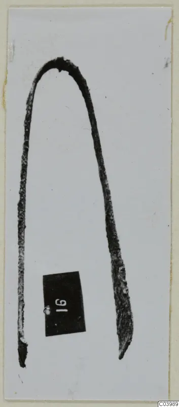 Bronze toilet requisite from Lapithos: a bent metal implement shaped like tweezers, with a number label beside it.