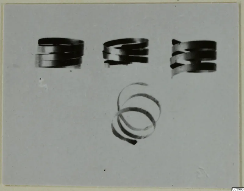 Three coiled spiral rings in a row above a single open spiral, on a plain grey background.