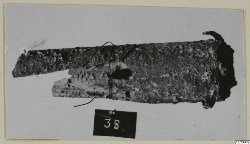 Corroded bronze tool fragment from Lapithos, Vrysi tou Barba tombs, shown with a number label